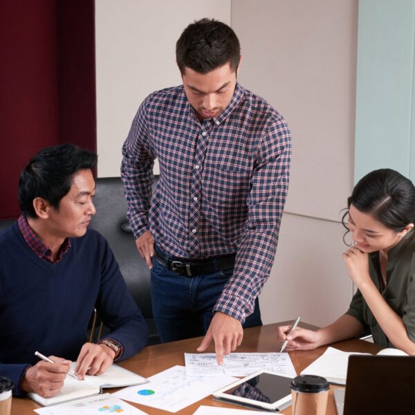 three-colleagues-discussing-business-report-examining-statistical-data-min